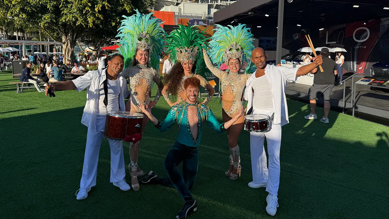 Professional Brazilian dancers for events in Miami posing in front of Hard Rock Stadium, featuring Samba performers in feathered costumes and live drummers for a StepFlix Entertainment show in South Florida.